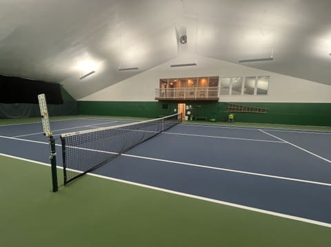 Court 1 from the net post, with a score marker on the post and the viewing balcony across the court.
